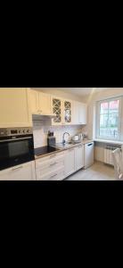 a kitchen with white cabinets and a sink and a window at Dom Na Fali in Pasym