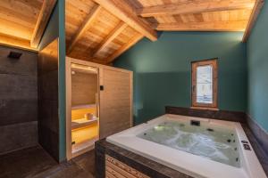a large tub in a bathroom with wooden ceilings at Shasta Mountain Lodge in Cavalese +24 photos