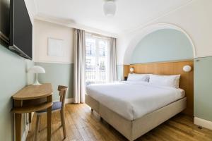 a bedroom with a bed and a desk and a tv at Hôtel Oratio in Paris +44 photos