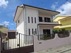 a white house with a black fence at Constança House in Corroios