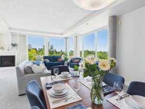 a living room with a table with a vase of flowers at Panoramic Ocean & Fairway Views At Sayward Hill in Victoria