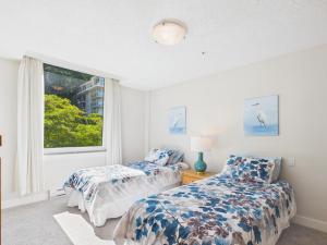 two beds in a room with a window at Panoramic Ocean & Fairway Views At Sayward Hill in Victoria