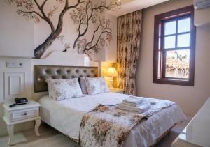 a bedroom with a bed with a tree mural on the wall at Kaleiçi Ozkavak Hotel in Antalya +177 photos