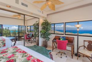 a bedroom with a bed and a desk and windows at 622 Kapalua Ridge Villa in Lahaina