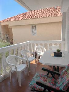 a balcony with white tables and chairs on a balcony at Apartman Dona in Petrovac na Moru
