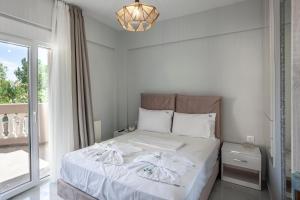 a bedroom with a bed with white sheets and a window at Villa Olia with private pool in Pefkochori