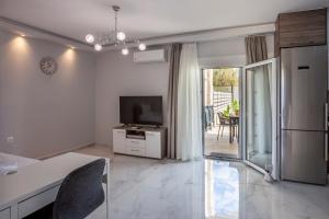 a white living room with a television and a table at Villa Olia with private pool in Pefkochori +56 photos