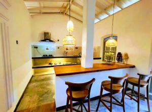 a kitchen with a counter and some chairs in it at Calm Villa in Mihiripenne
