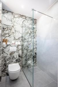 a bathroom with a toilet and a stone wall at Villa Olia with private pool in Pefkochori