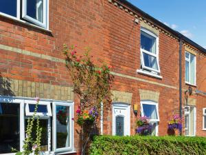 a red brick house with flowers in the windows at Billada Cottage in Firsby