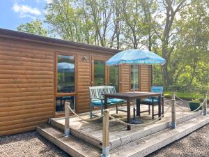 a wooden deck with a table and chairs and an umbrella at Ridge View Lodge - Uk49924 in Dumfries