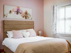 a bedroom with a bed with pink and white pillows at One The Old Stables in Knitsley