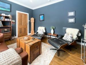 a living room with blue walls and leather chairs at Taigh Beag in Stranraer