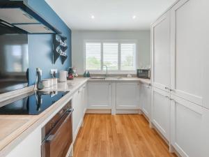 a kitchen with white cabinets and a blue wall at Taigh Beag in Stranraer +18 photos