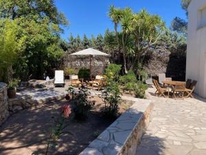 a patio with an umbrella and a table and chairs at Villa "LES ALIZES" Côté jardin - Bord de mer in Saint-Raphaël