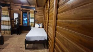 ein Schlafzimmer mit einem Bett in einem Zimmer mit Holzwänden in der Unterkunft Sandy Beach Hotel in Arugam Bay
