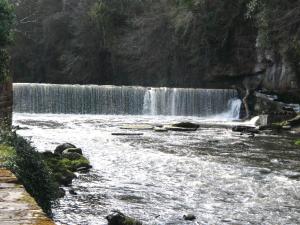 a river with a waterfall in front of a mountain at Quay Cottage in Cramond