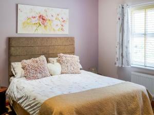 a bedroom with a bed with pillows and a painting at Two The Old Stables in Knitsley