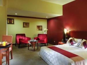 a hotel room with a bed and two red chairs at Mercure Jakarta Kota in Jakarta +72 photos