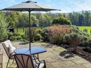 a table with an umbrella on a patio at Three The Old Stables in Knitsley