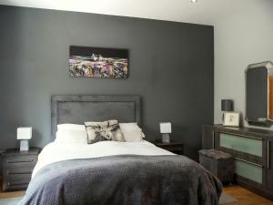 a bedroom with a bed with a gray wall at Three The Old Stables in Knitsley
