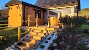 a wooden cabin with a staircase leading to a house at Domy na Spiszu in Czarna Góra