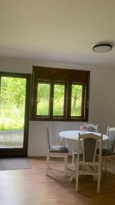 a dining room with a table and chairs and windows at Apartman Dream in Foča