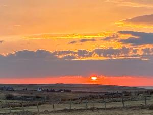 a sunset in a field with the sun setting at Go Ye Cottage in Leurbost