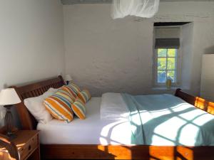 a bed with orange and blue pillows and a window at La Bordeneuve - Chambre d'hôtes in Auch