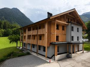 a house with a wooden facade with mountains in the background at Demlhof, Gästehaus in Finkenberg