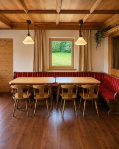 a dining room with two tables and a red couch at Demlhof, Gästehaus in Finkenberg