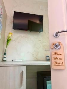 a flat screen tv hanging on a wall with a shelf at Maria House in Parghelia