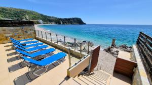 a beach with blue lounge chairs and the ocean at Mare Beachfront Rooms Himare in Himare