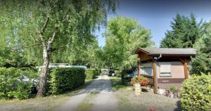 a driveway leading to a house with trees and flowers at Camping la Chaumière in Heimsbrunn