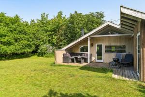 a small house with a deck and a yard at Charming Cottage Near The Water in Holbæk +9 photos
