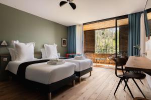 a bedroom with two beds and a desk and a window at Le Moulin de Nouara in Ambert