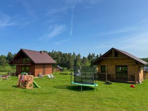 a log cabin with a playground in the grass at Chatki Bies-Czadowe-Czad in Berezka