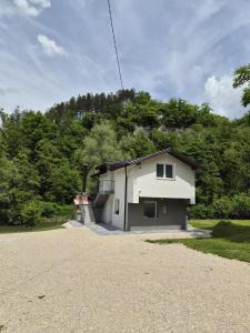 a white house with a hill in the background at Apartmani Lucica in Jajce