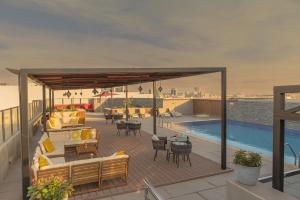 a deck with furniture and a swimming pool on a roof at The Grand Lux Hotel in Doha
