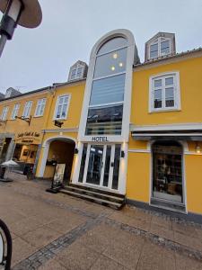 a yellow building with a hotel on a street at Quiet Blue Room 2 on pedestrian street Saeby in Sæby