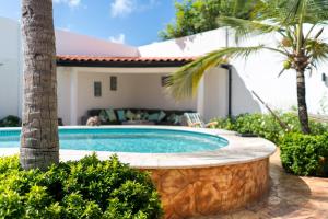 uma piscina com uma palmeira e uma casa em Cas Elizabeth em Palm-Eagle Beach