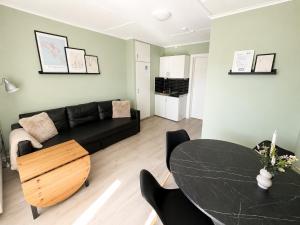 a living room with a black couch and a table at Lillehammer Camping - Sentrums leilighet in Lillehammer