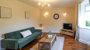a living room with a green couch and a tv at Spacious and Modern Durham home in Gilesgate