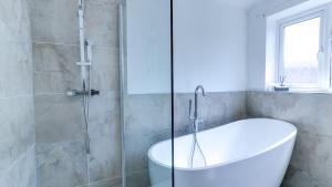 a bathroom with a tub and a glass shower at Spacious and Modern Durham home in Gilesgate