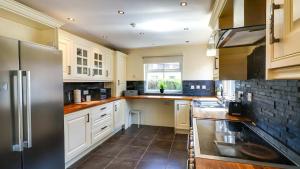a kitchen with white cabinets and a stainless steel refrigerator at Spacious and Modern Durham home in Gilesgate