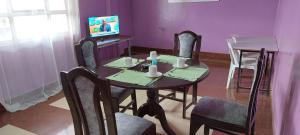 a dining room with a table and chairs and a tv at Crown Accommodation Narok in Narok +7 photos