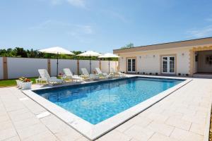 a swimming pool with chairs and umbrellas in a backyard at Villa Kaplan Verde in Stolac