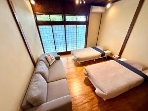 a living room with two beds and a couch at SADO Stay 02 金山京町一軒家貸し切り in Sado