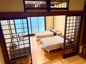 a room with two beds in a room with windows at SADO Stay 02 金山京町一軒家貸し切り in Sado