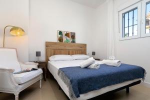 a white bedroom with a bed and a chair at Sunstay Arroyo House Velez in Vélez-Málaga